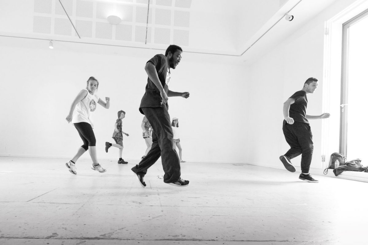 A group of dancers rehearse in an open-plan minimalist studio