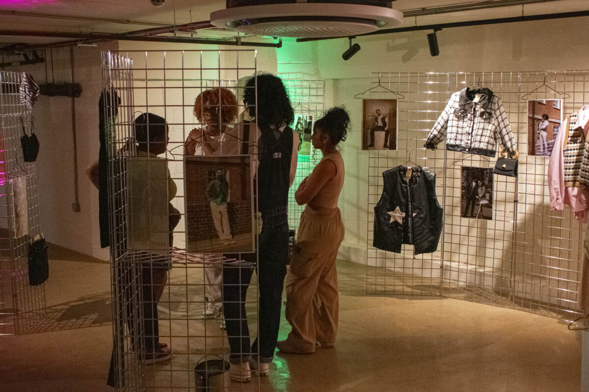 visitors viewing a visual arts exhibition with fashion props hanging on wire frames