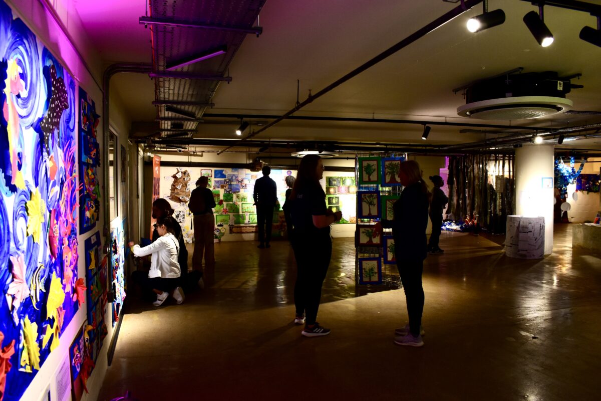 Open plan exhibition space in FUSEBOX, a basement venue, filled with artwork and audiences