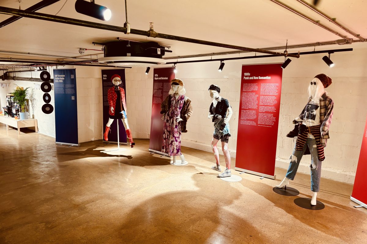 four mannequins in fashion from 70s-90s, alongside rollerbanners with heritage information