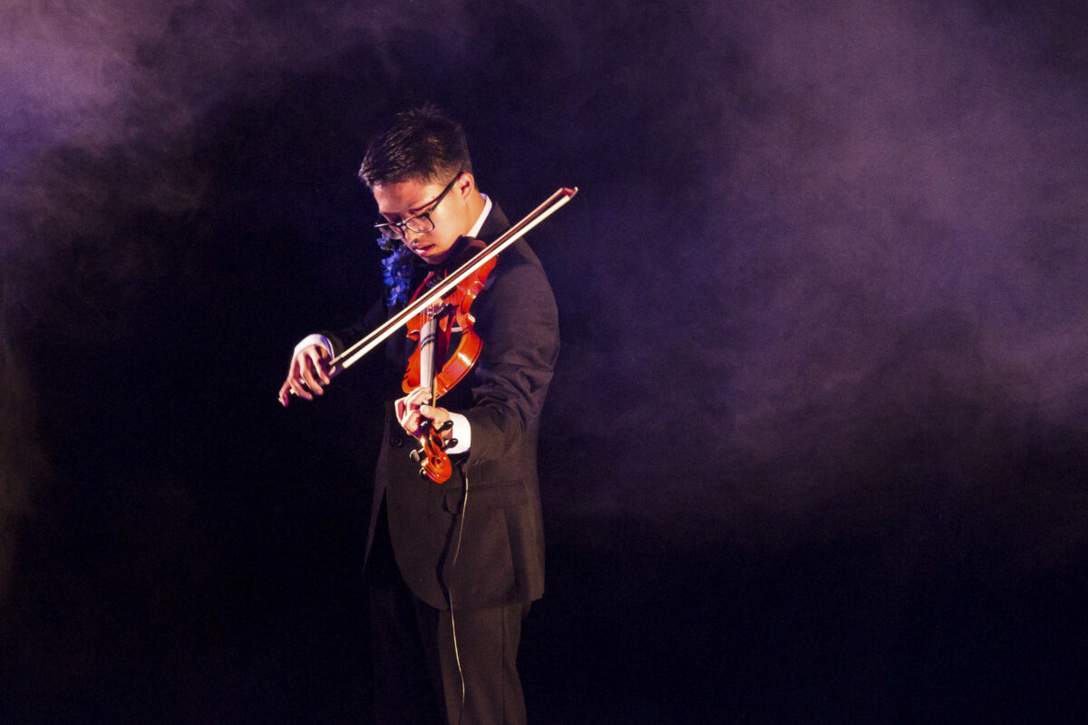 A violinist on stage surrounded by smoke
