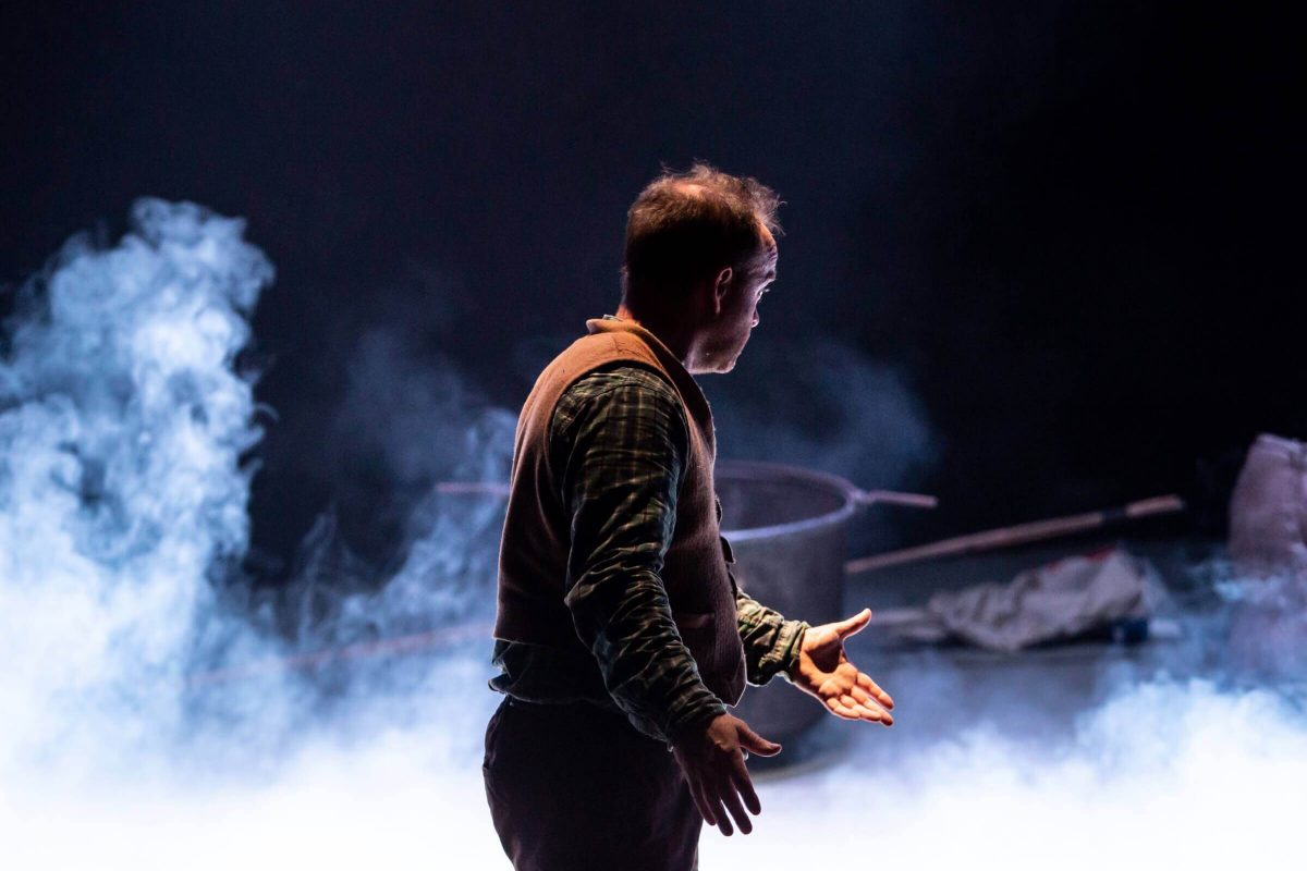 a performer faces away from the camera with smoke surrounding him